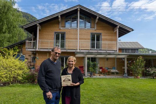 Ehepaar Schmeidl mit "Haus des Monats" Plakette vor ihrem renovierten Wohnhaus im Garten